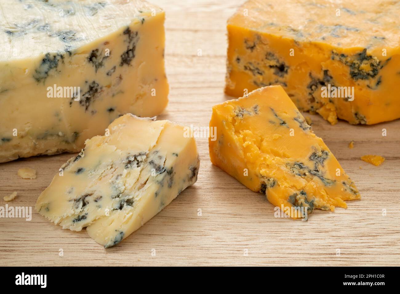 Ein Stück englischer Shropshire Blue Cheese und ein Stück Stilton-Käse auf einem Schneidebrett für einen Snack aus nächster Nähe Stockfoto