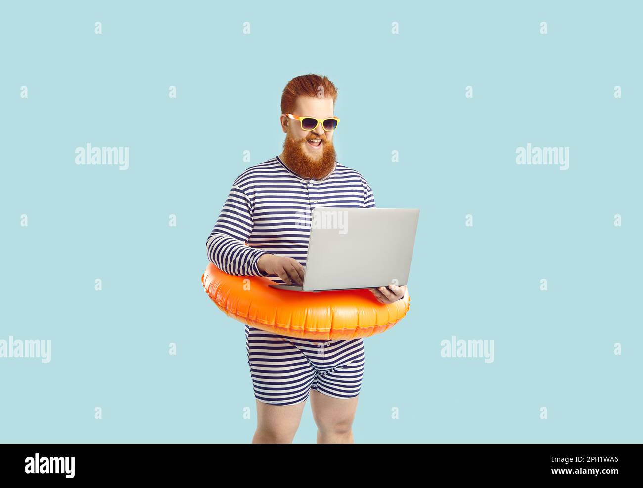 Lustiger Mann in Erwartung des Sommerurlaubs mit Laptop-Buchung auf hellblauem Hintergrund. Stockfoto