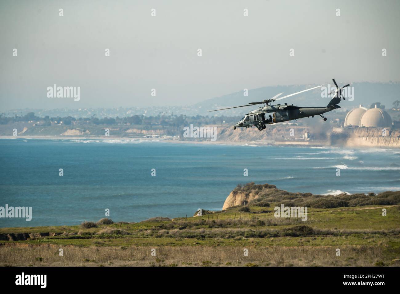 DIE US Navy MH60S fliegt zwischen einem Versorgungsschiff und der Küste durch Camp Pendleton entlang der kalifornischen Küste. Stockfoto