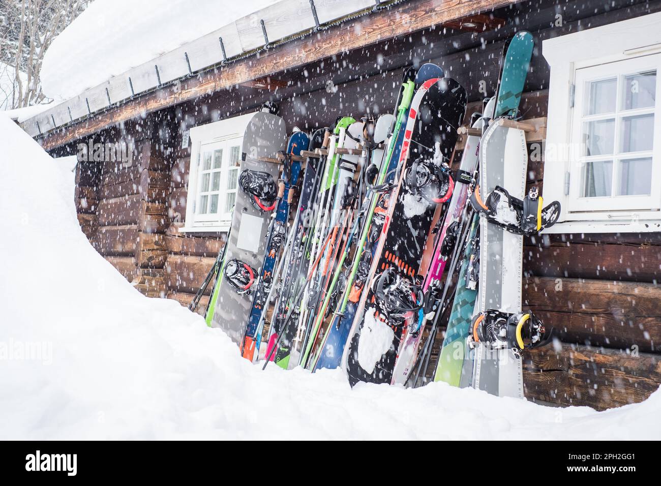 Hemsedal, Norwegen - 13. März 2023: Bergskier und Snowboards stehen während des Schneefalls auf einer Holzkabinenwand. Stockfoto