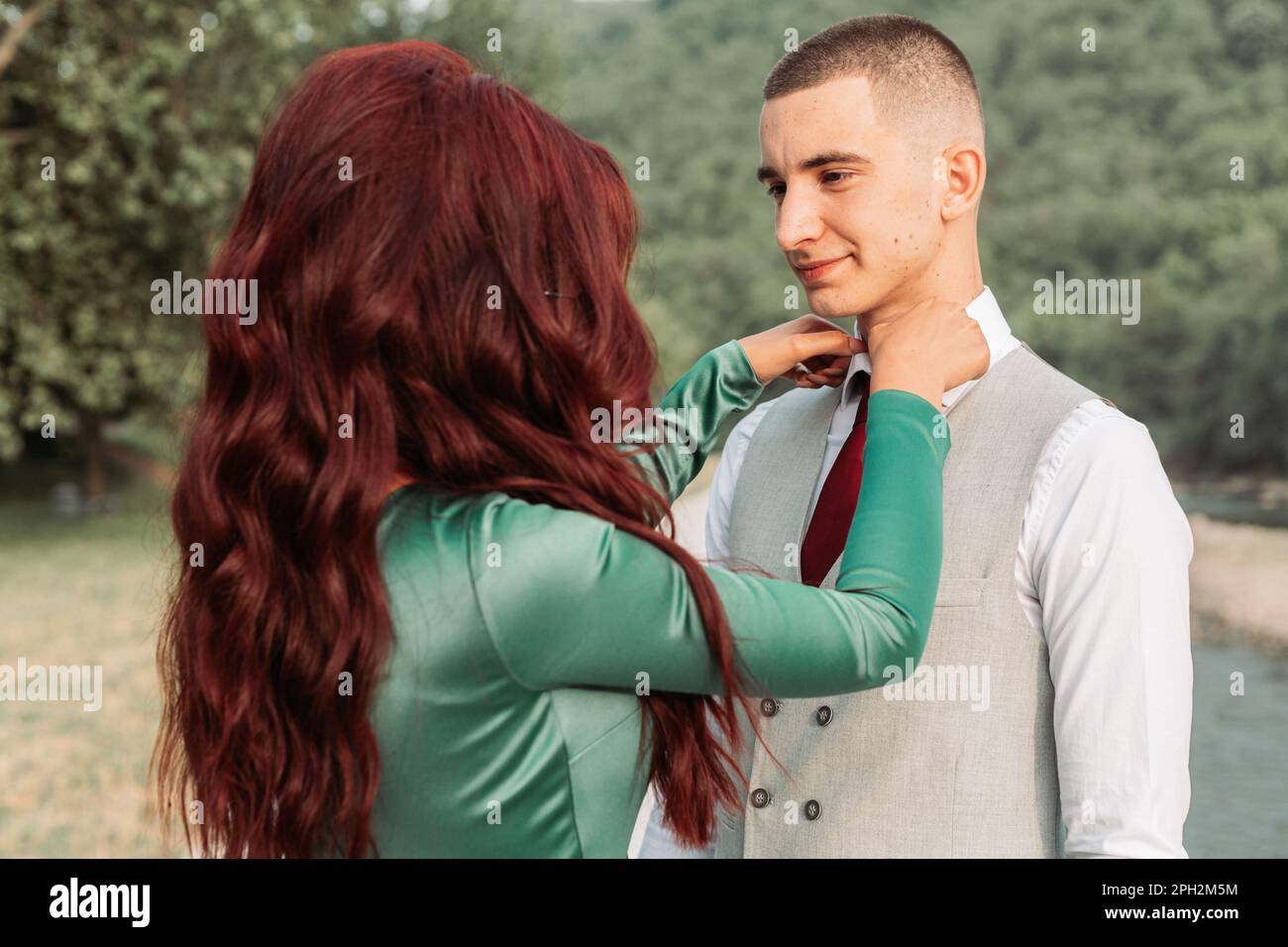 Junge Frau, die eine Krawatte für ihr Abschlussball-Date repariert Stockfoto