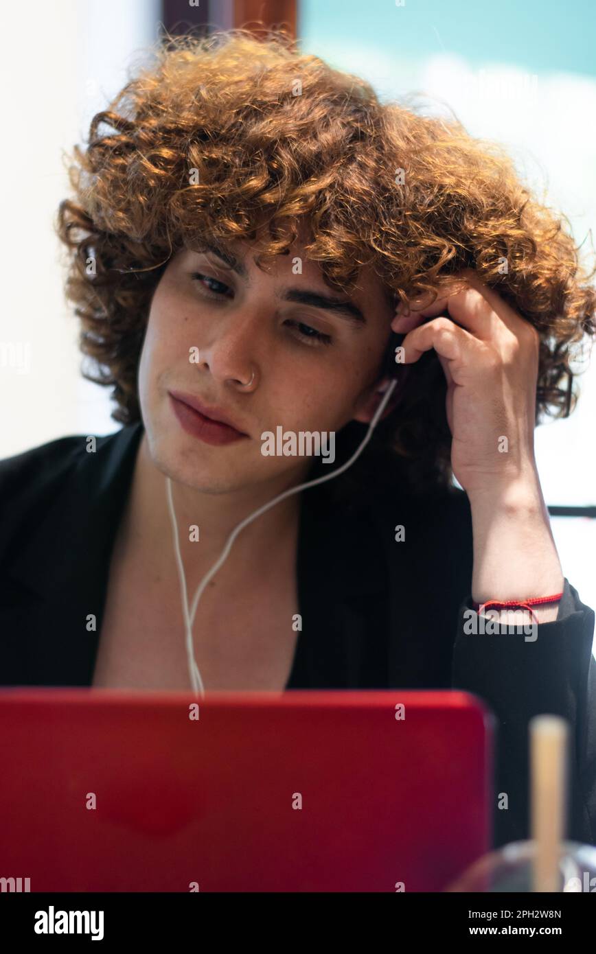 Eine nicht binäre Person beobachtet den Laptop-Bildschirm und berührt ihren Kopf Stockfoto