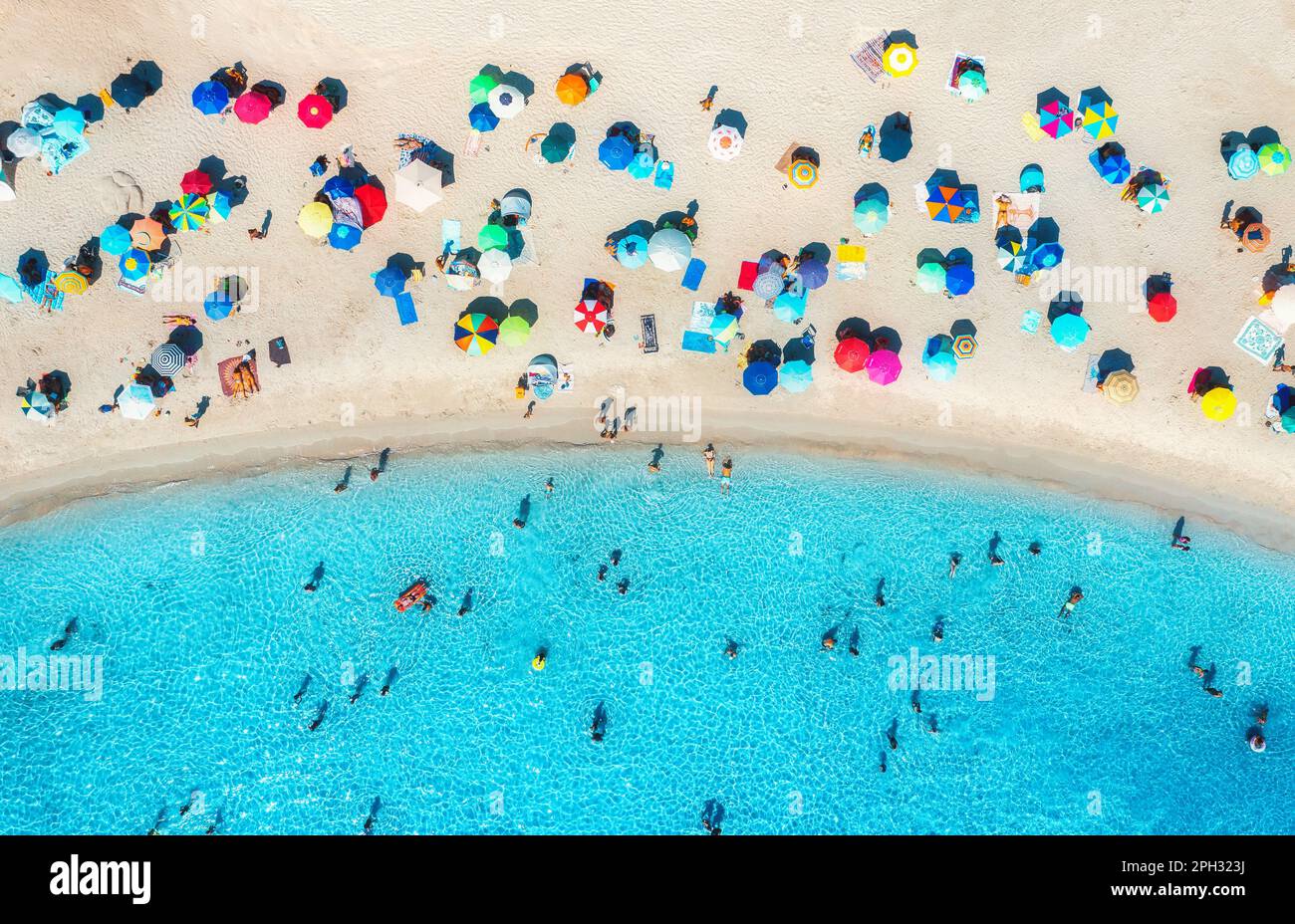 Luftaufnahme von bunten Sonnenschirmen am Strand, Menschen im blauen Meer Stockfoto