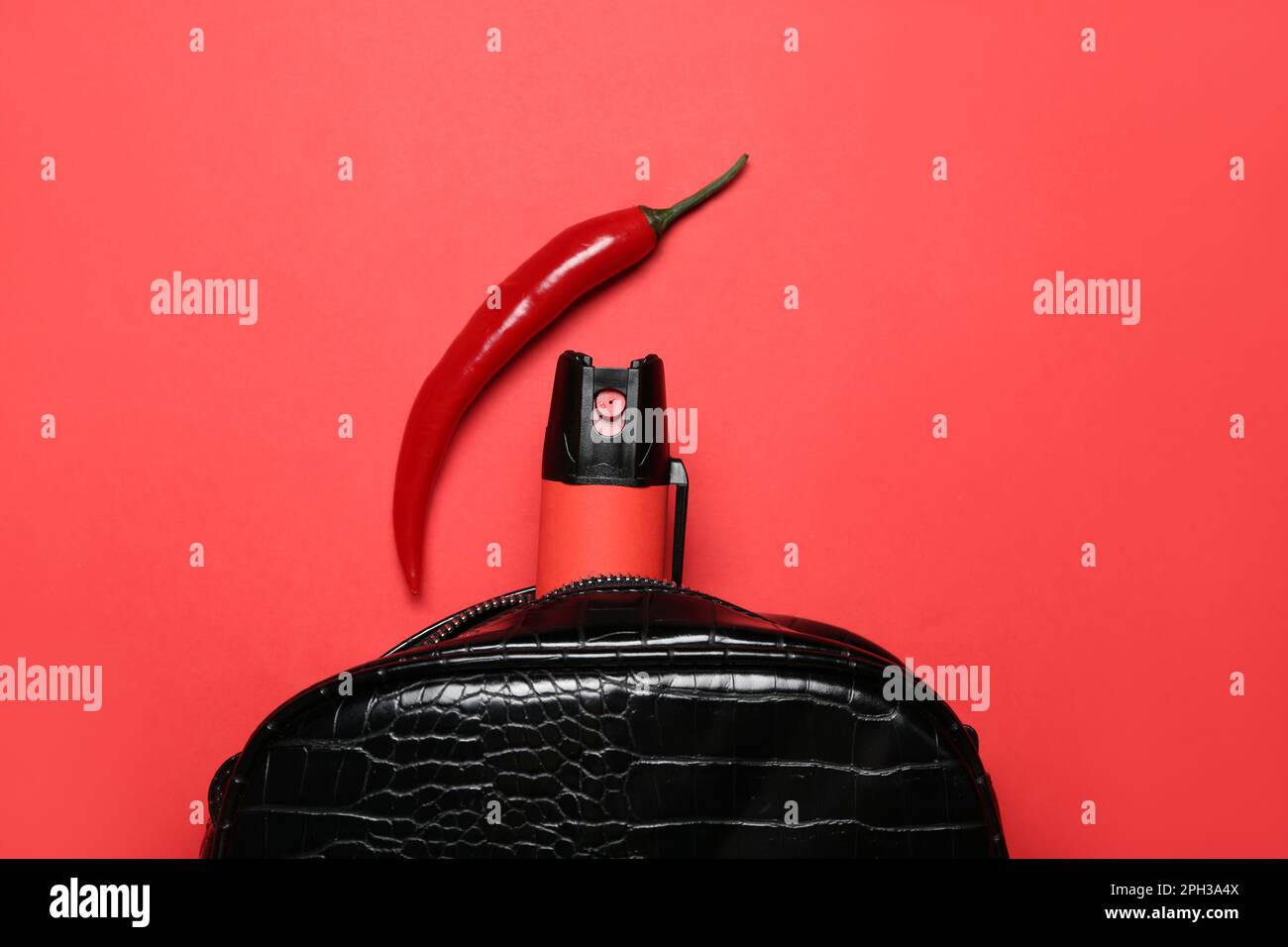 Beutel mit Spray und Chili-Pfeffer auf rotem Hintergrund, Nahaufnahme Stockfoto