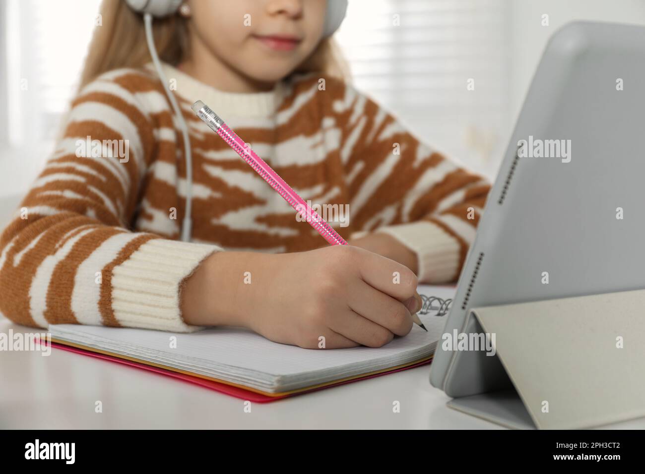 Süßes kleines Mädchen mit modernem Tablet, das zu Hause online lernt, Nahaufnahme. E-Learning Stockfoto