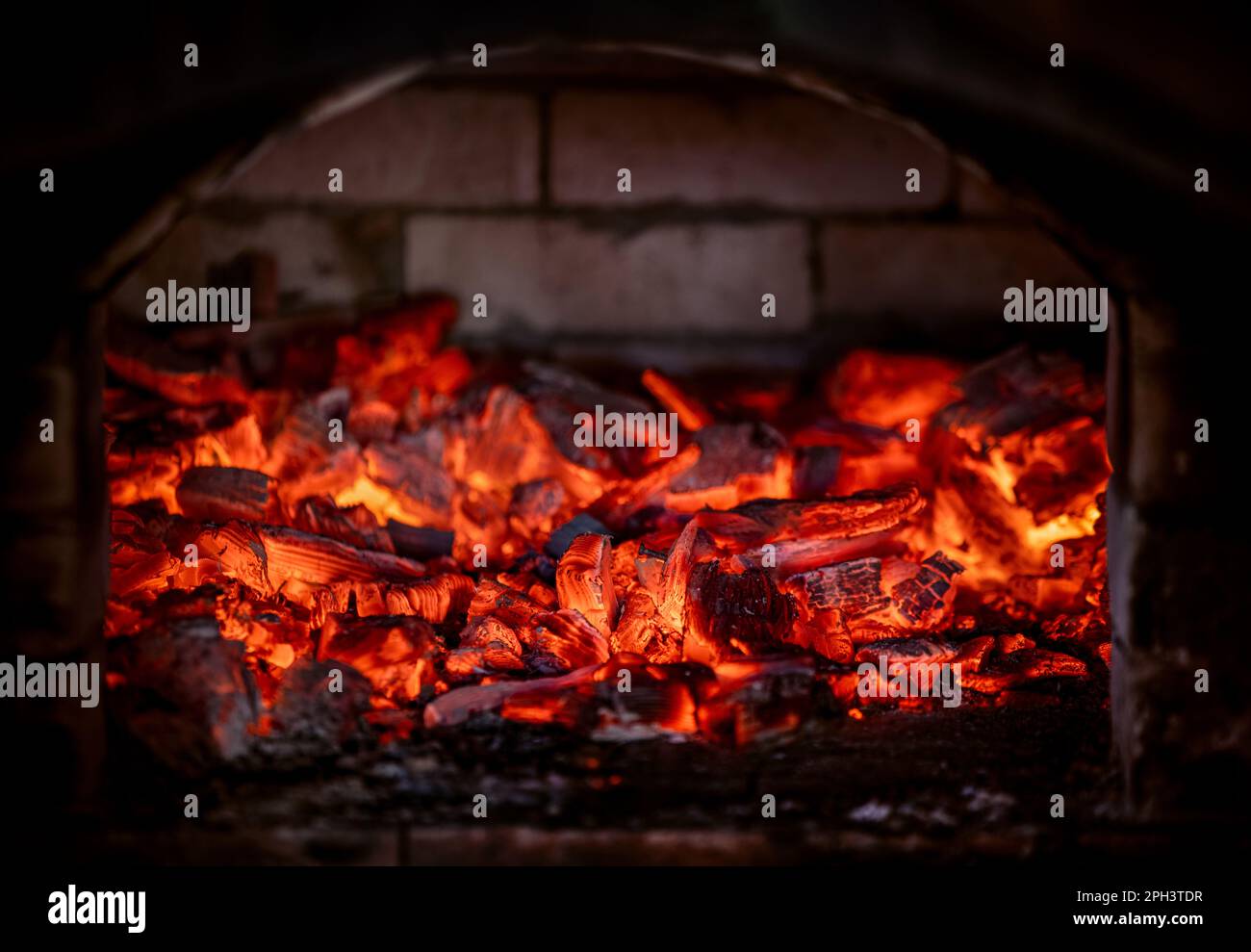 Flamme des Feuers von heißen brennenden Kohlen im Kamin. Wärme aus dem Ofen. Stockfoto