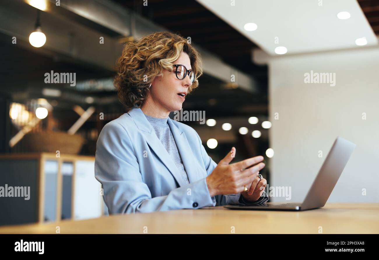 Eine Geschäftsfrau, die in einem Videogespräch in einem Büro mit Kollegen spricht. Eine Geschäftsfrau, die ein Online-Meeting mit ihrem Team abhält. Professionelle Geschäftsfrau Stockfoto