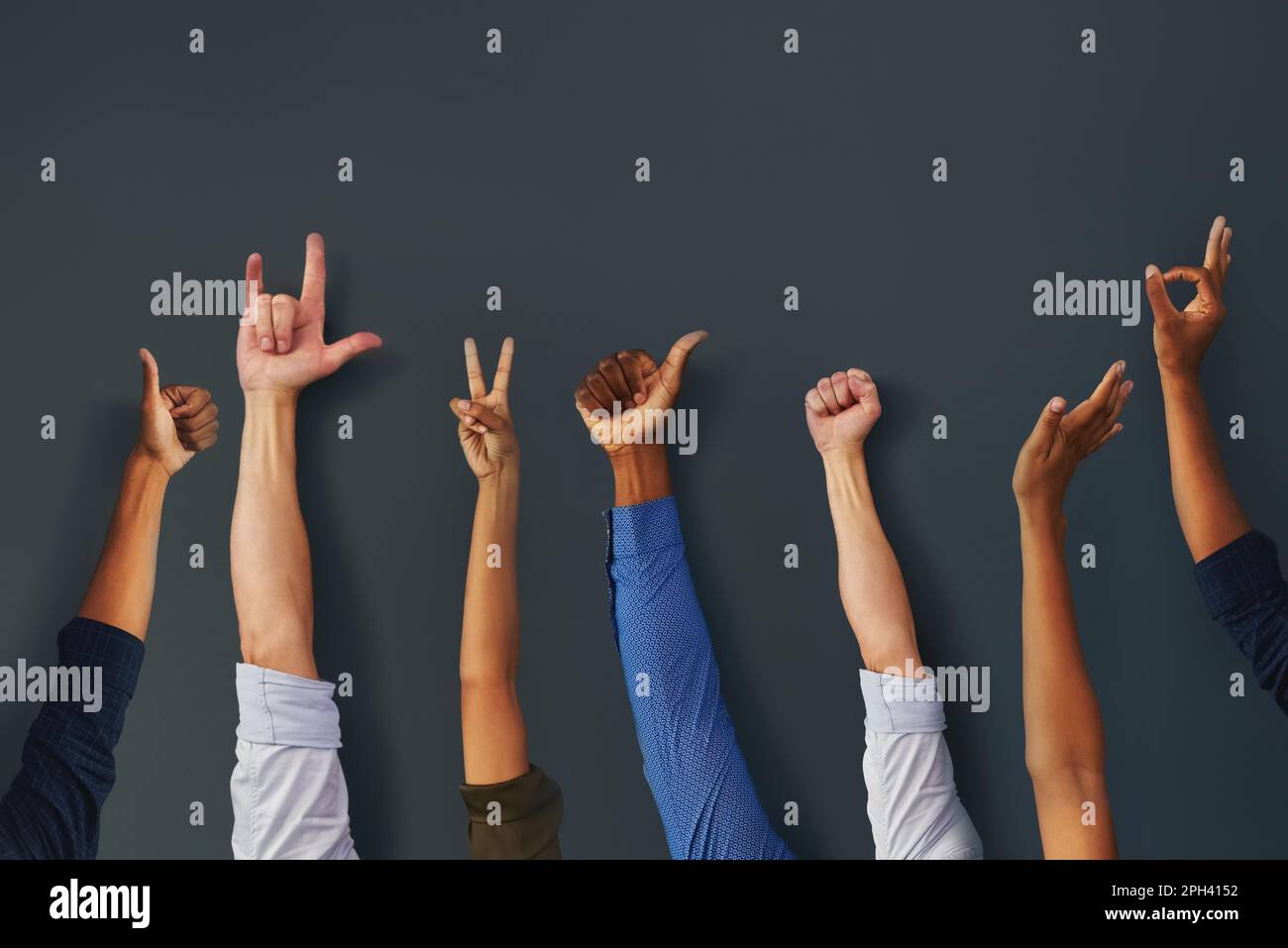 Nehmt die Hände hoch, Jungs. Eine Gruppe nicht wiedererkennbarer Menschen, die ihre Hände hochhalten und verschiedene Arten von Handgesten in einem Gebäude zeigen. Stockfoto
