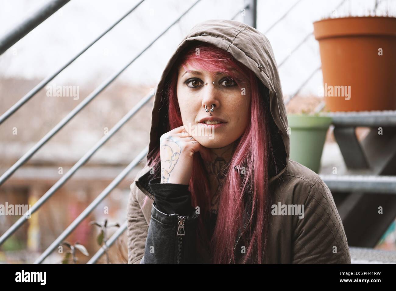Porträt einer nachdenklichen jungen Frau mit Piercings und Tattoos auf der Außentreppe Stockfoto