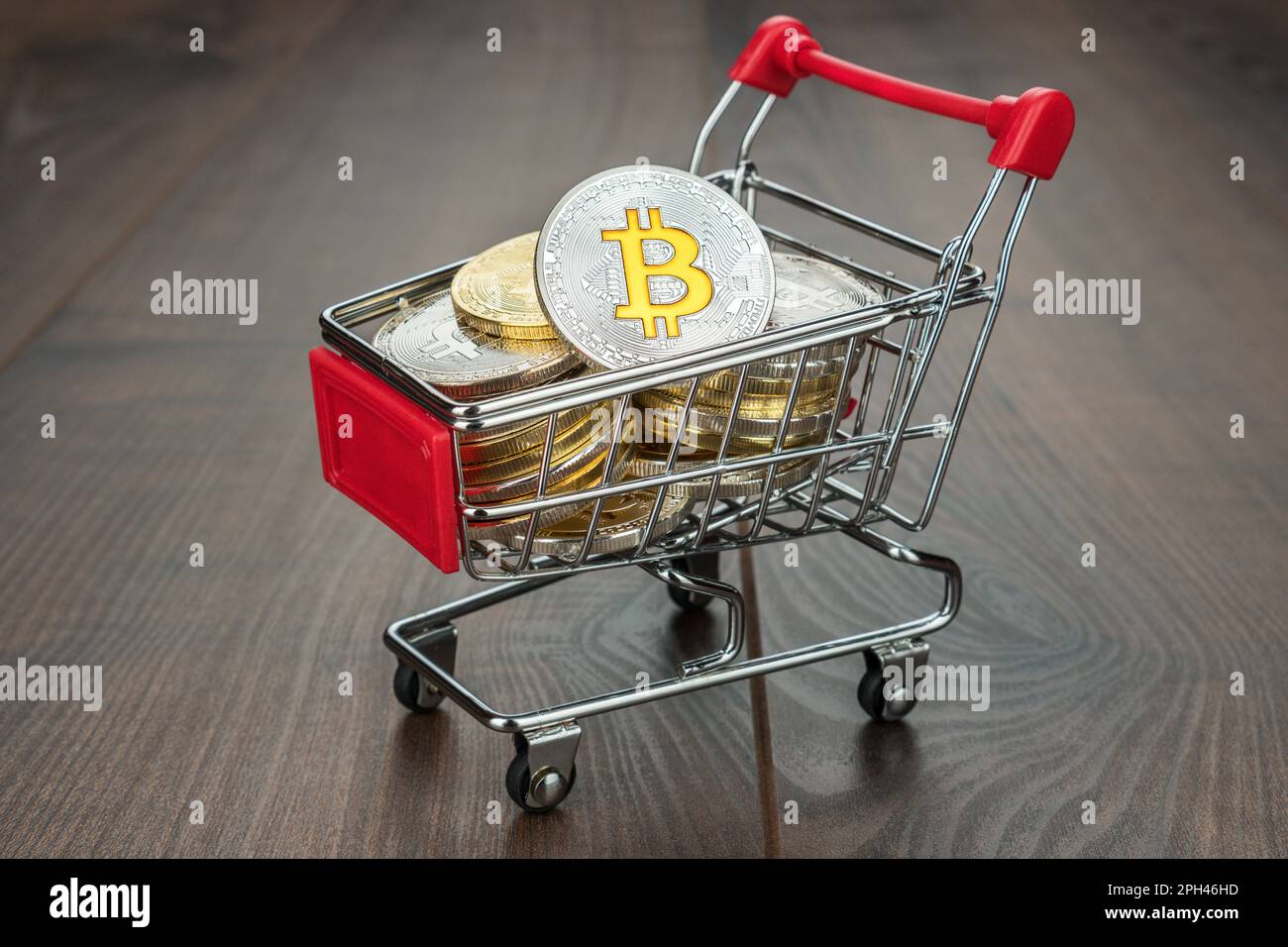 Einkaufswagen mit Bitcoin-Währungskonzept auf Holzhintergrund Stockfoto