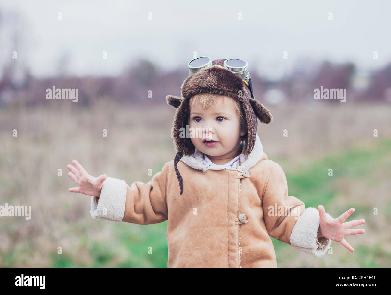 Das charmante Baby in Pilotenkleidung hob die Hände, als ob es fliegen würde Stockfoto