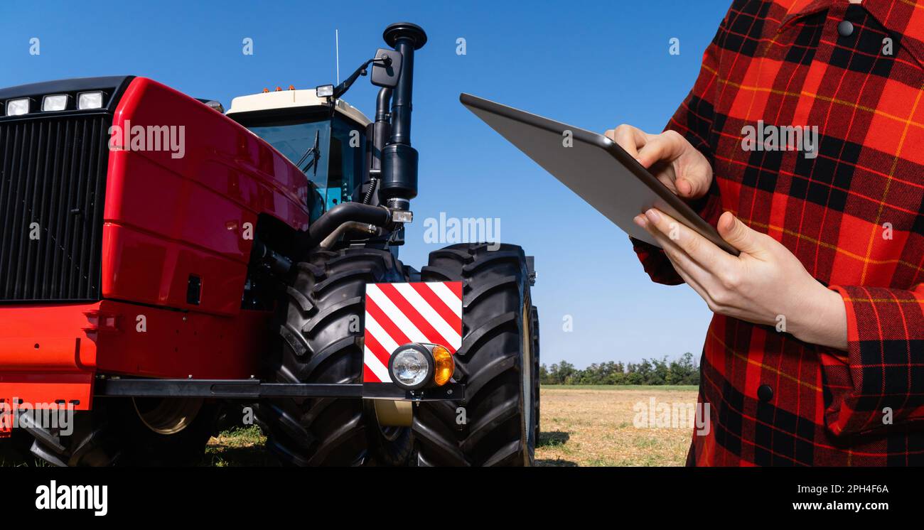 Ein Landwirt mit einem digitalen Tablet steuert einen autonomen Traktor auf einem intelligenten Betrieb. Hochwertiges Foto Stockfoto