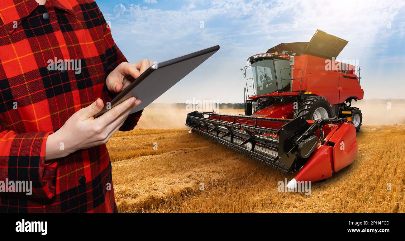 Landwirt mit digitalem Tablet im Hintergrund der Erntemaschine. Konzept der intelligenten Landwirtschaft. Hochwertiges Foto Stockfoto