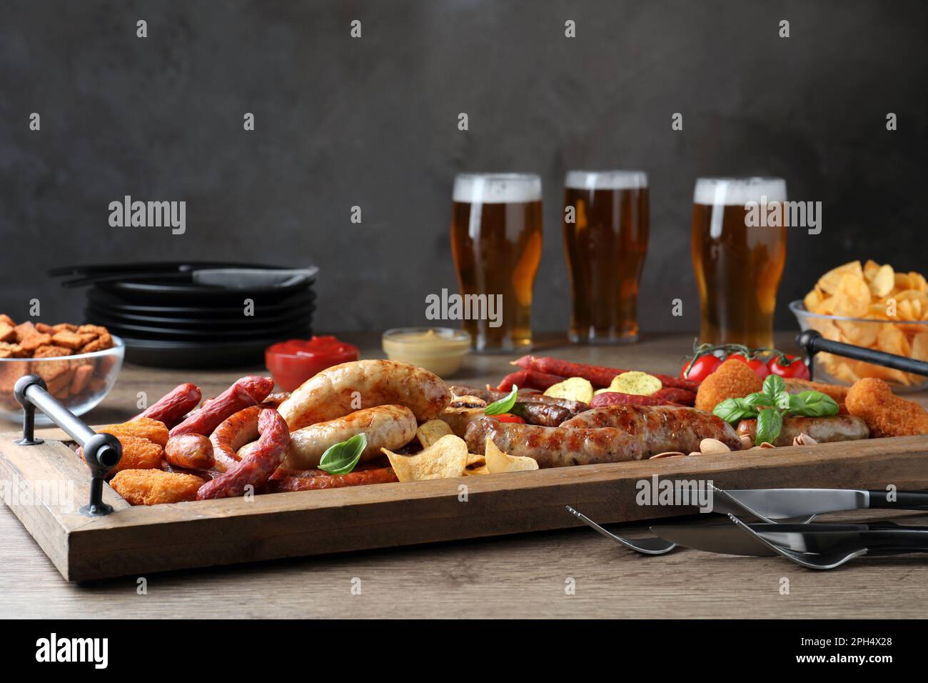 Verschiedene leckere Snacks und Bier auf einem Holztisch Stockfoto