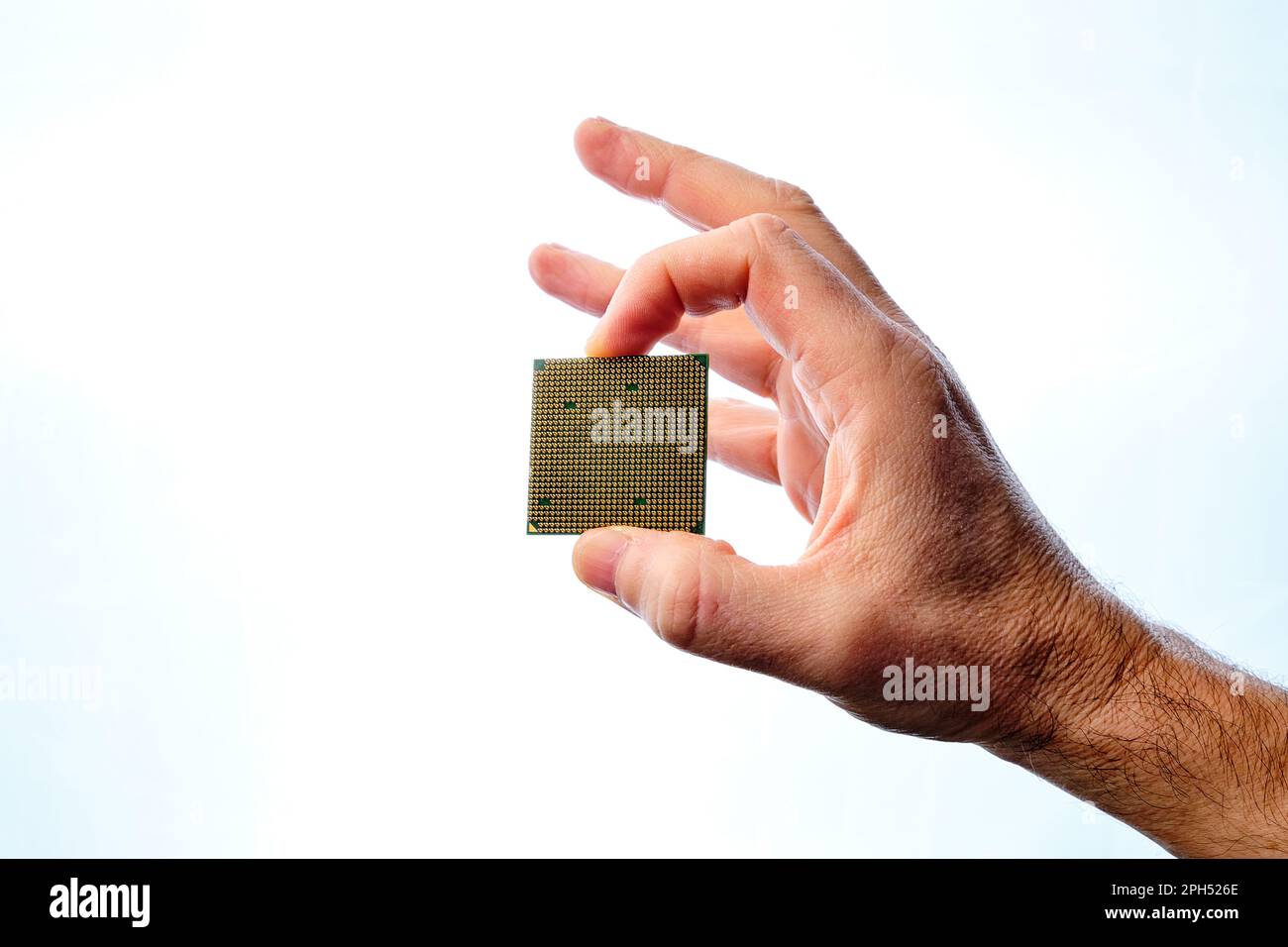 Die Hand eines Mannes, der einen Mikrochip mit zwei Fingern auf weißem Hintergrund hält. Stockfoto