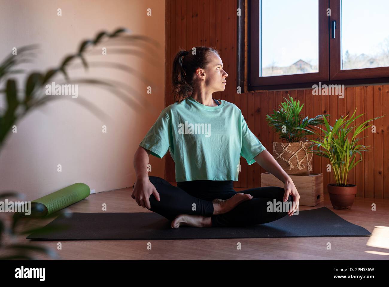 Eine Frau, die zu Hause auf einer Yoga-Matte sitzt und meditiert Stockfoto