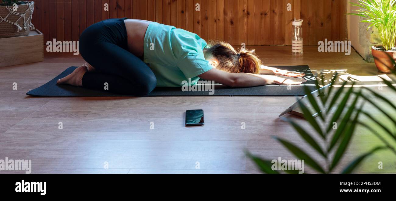 Ruhige Frau, die zu Hause Yoga macht und entspannende Übungen macht. Stockfoto