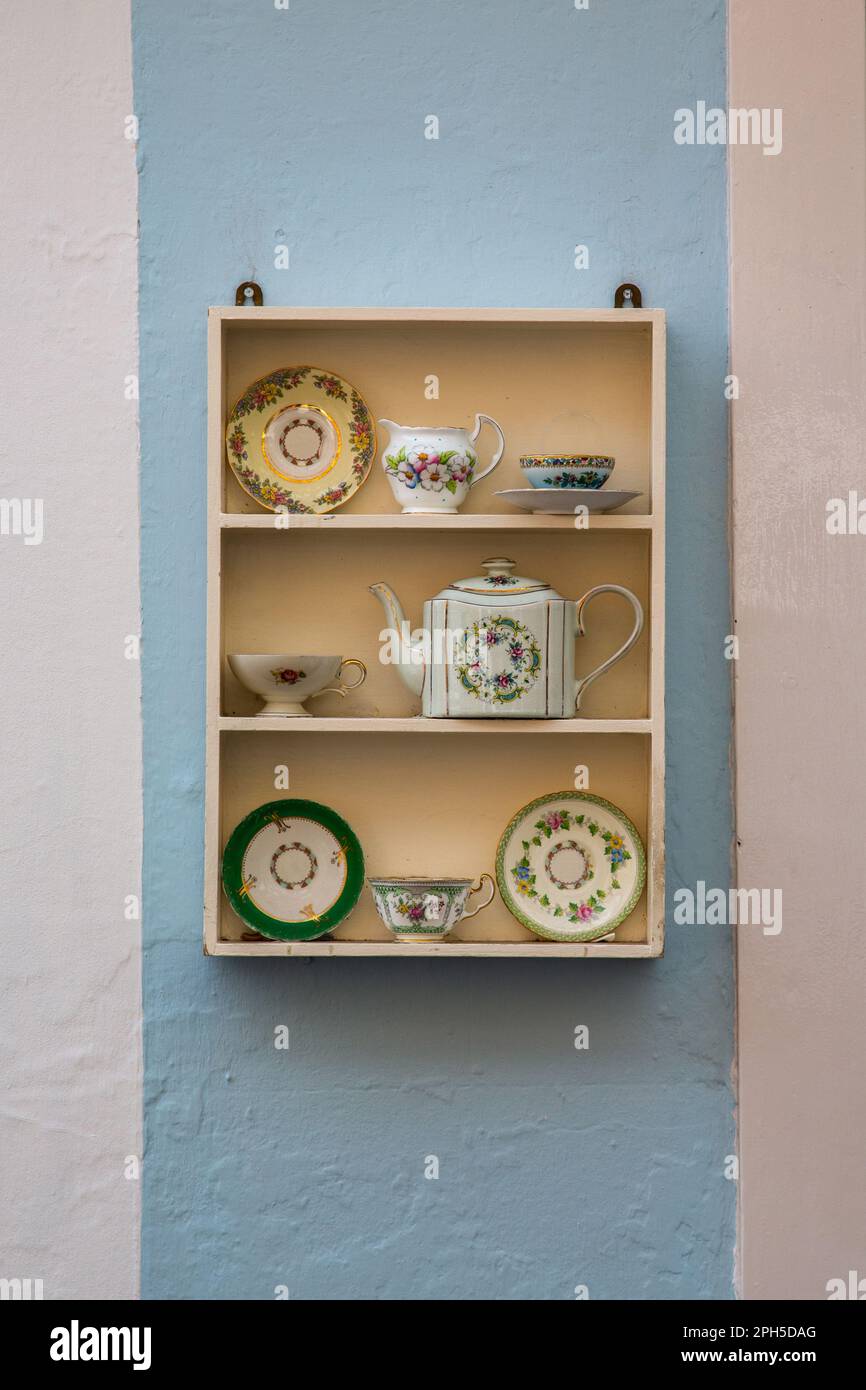 Ein Regal mit einer porzellan-Teekanne mit Blumenmuster, einem Milchkännchen und Untertassen. Teehaus oder Teestube. Stockfoto