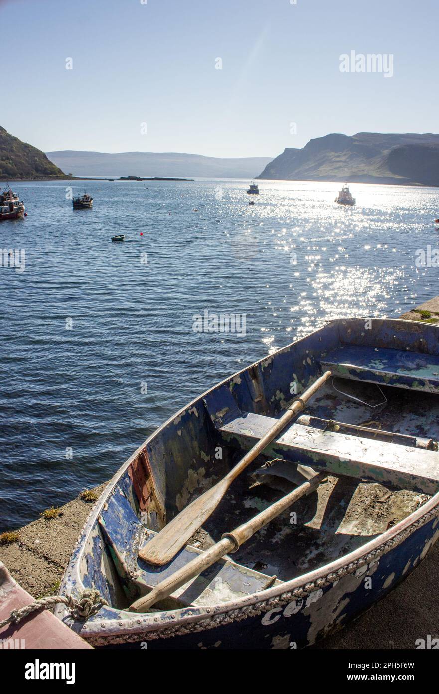 Leeres gestrandetes Ruderboot, mit der Bucht im Hintergrund, im Dorf Portree auf der Ilse von Skye Stockfoto
