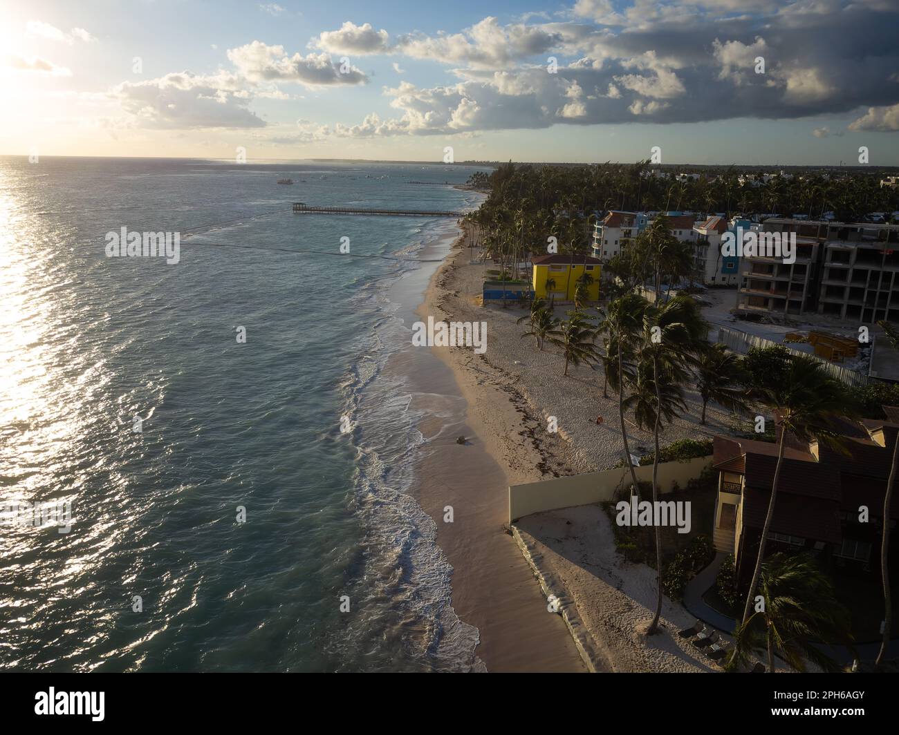 Abendlicher Ferienort am Meer. Wolkiger Himmel, ruhiges Meer. Tropische Pflanzen. Reisen, Erholung, Tourismus, Unternehmen, Infrastruktur, meteorologie. Stockfoto