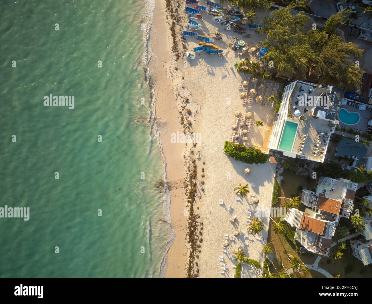 Elite-Resort-Komplex am Meer. Große Hotels, kleine Bungalows, Pools inmitten von Palmen. Am Ufer gibt es Sonnenliegen, Boote, Strandschirme Stockfoto