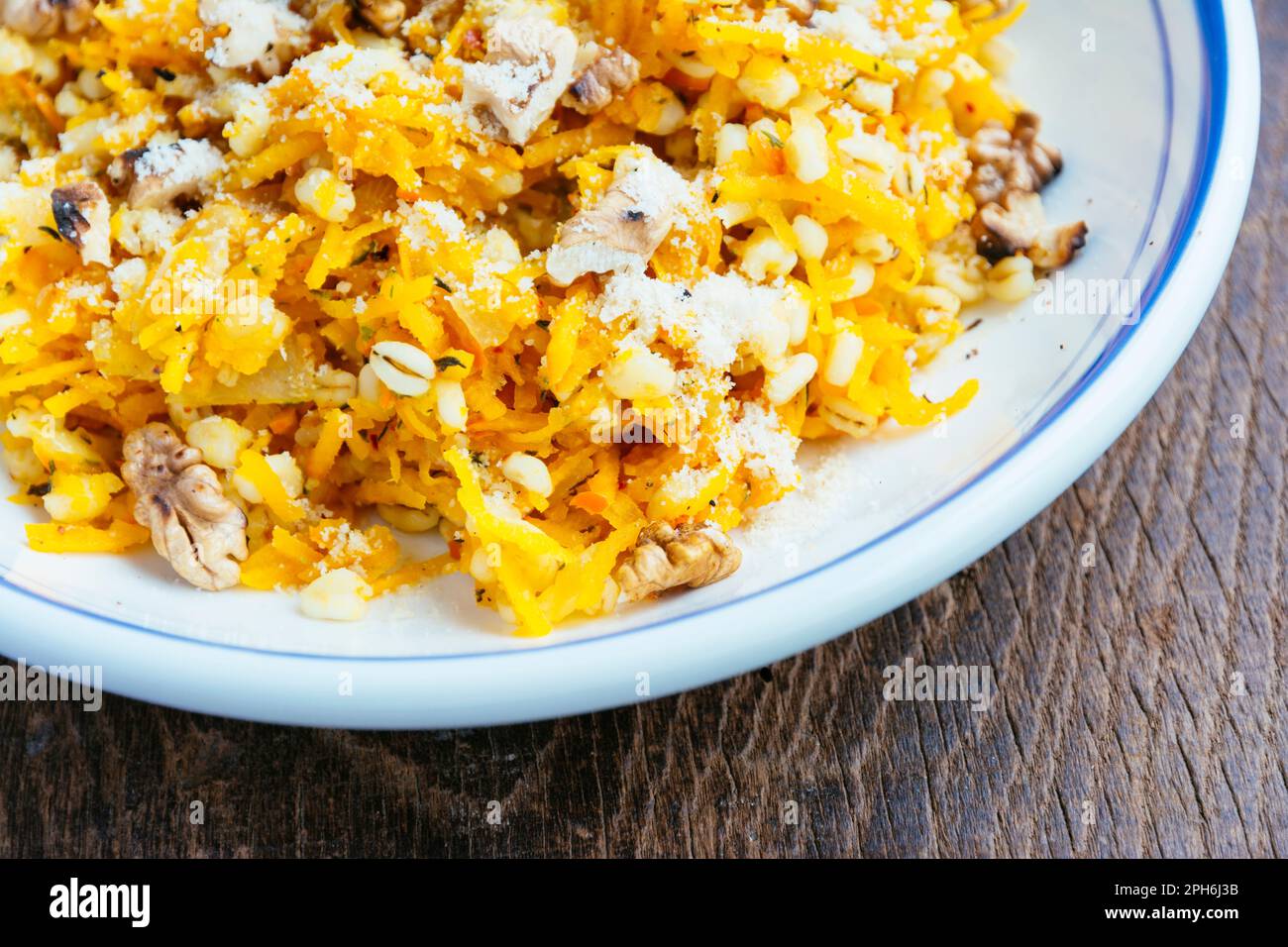 Gersten-Orzotto mit Winterkürbis und gerösteten Walnüssen. Stockfoto