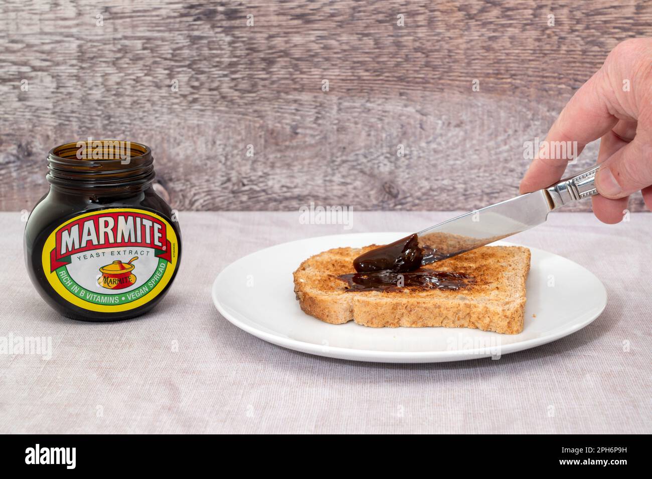 London, Vereinigtes Königreich - 21. März 2023 : Marmite wird auf einer Scheibe getoastetes Brot gestreut. Marmite ist ein Hefeextrakt, der reich an Vitamin B ist Stockfoto