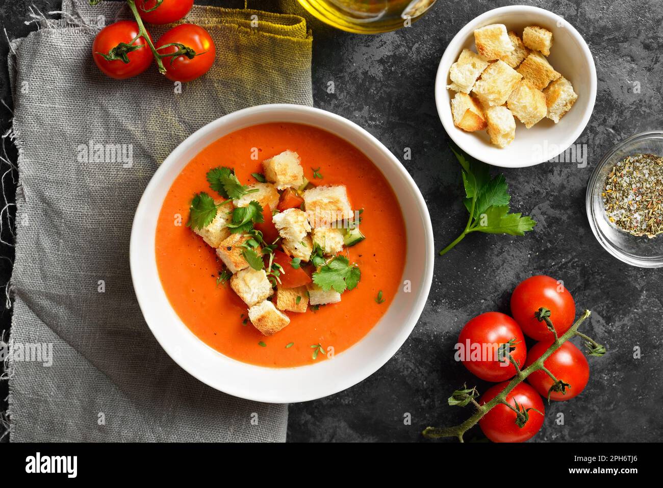 Tomaten-Gazpacho-Suppe mit Croutons in der Schüssel auf dunklem Steinhintergrund. Kalte Sommersuppe. Draufsicht, flach liegend Stockfoto