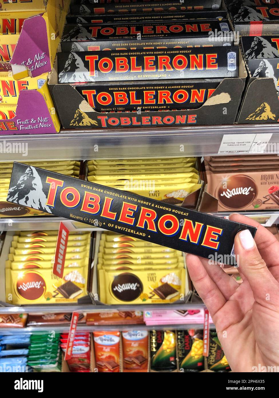 25.03.2023 Ukraine, Charkov Chocolate Toblerone in der Hand. Köstliche Schokolade in den Regalen. Schweizer dunkle Schokolade mit Honig-Mandel-Nougat Stockfoto