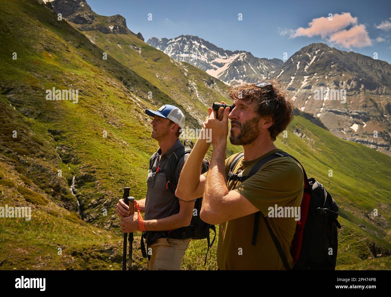 Nahporträt von zwei Bergsteigern, die durch das Fernglas auf der Suche nach Gipfeln zum Aufsteigen schauen, im Hintergrund können Sie andere Berge mit Strom sehen Stockfoto