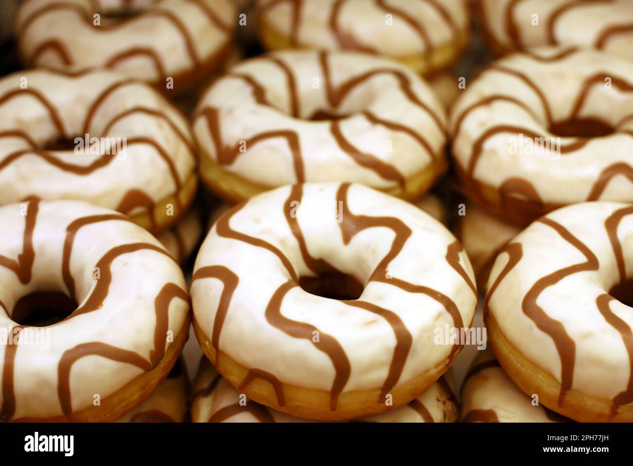 Doughnuts in weißer Glasur Nahaufnahme. Süße Donuts in einem Laden, kalorienreiches Essen Stockfoto