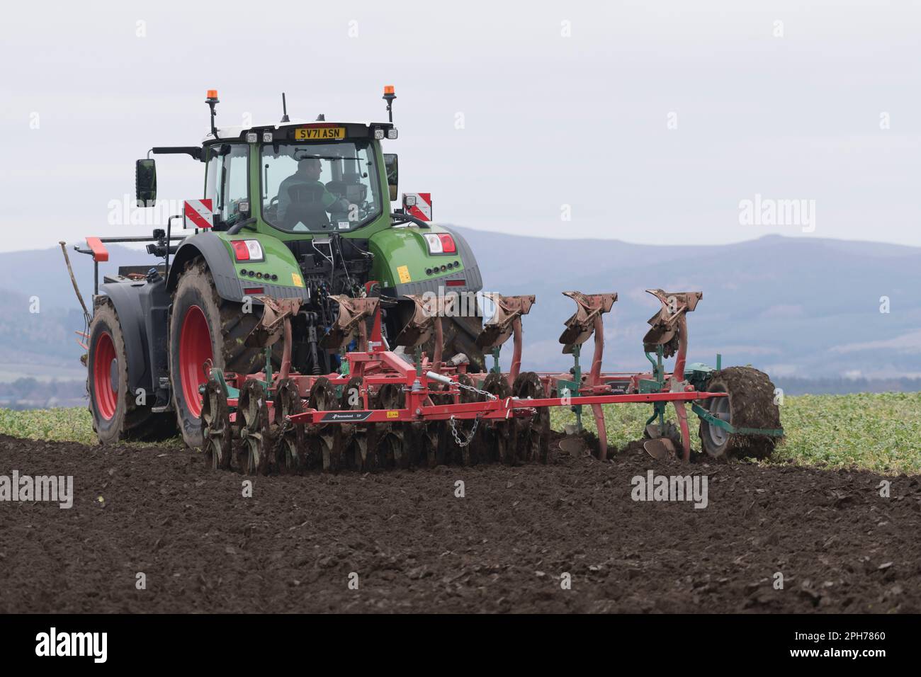 Ein Fendt-Traktor, der im Frühjahr mit einem Kverneland-Umkehrpflug und einem Doppelpacker in Gründung (Vetch) pflutet Stockfoto