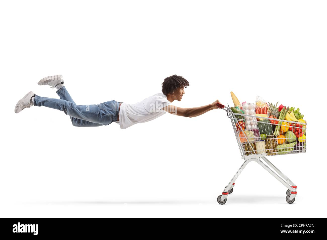 Ein afroamerikanischer Kerl fliegt und hält einen Einkaufswagen mit gesundem Essen isoliert auf weißem Hintergrund Stockfoto