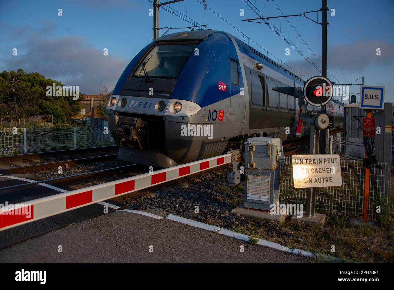 Ein Regionalzug des französischen Betreibers SNCF nähert sich einem Bahnübergang in der Nähe von Narbonne in Südfrankreich. Stockfoto