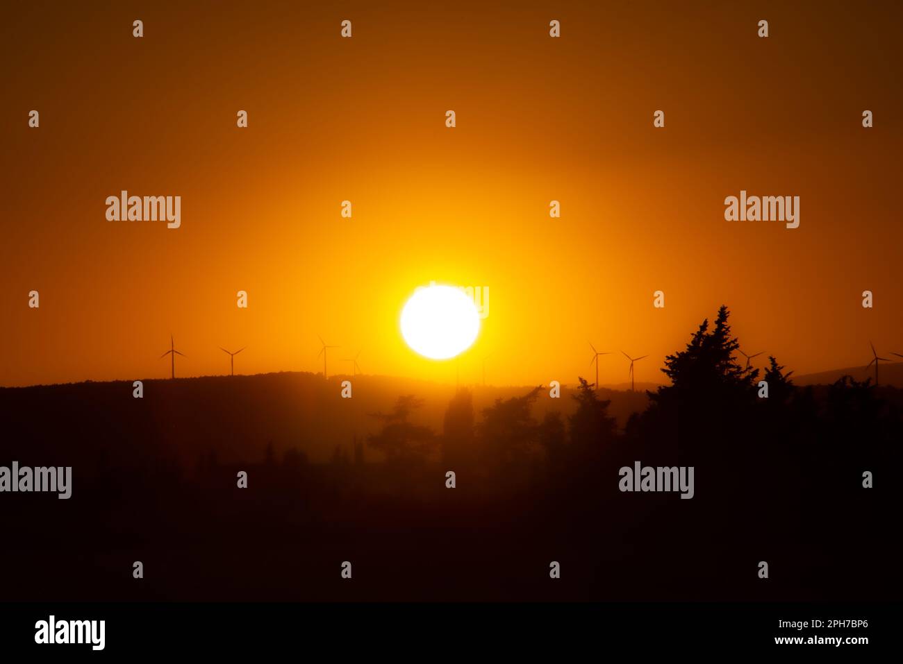 Sonnenuntergang über einer Windturbinenlinie auf einem Gebirgskamm in Südfrankreich. Sonne und Wind - die Zukunft der Energie. Stockfoto