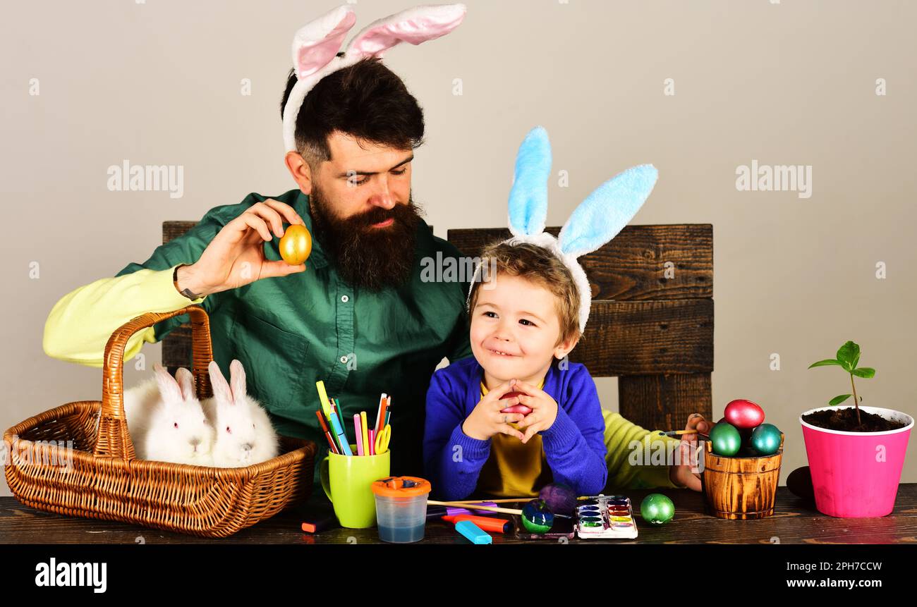 Vater und kleiner Sohn bereiten sich auf Osterferien vor. Eierjagd. Osterfamilientraditionen. Lächelnder Dad und ein süßer Junge in Hasenohren Stockfoto