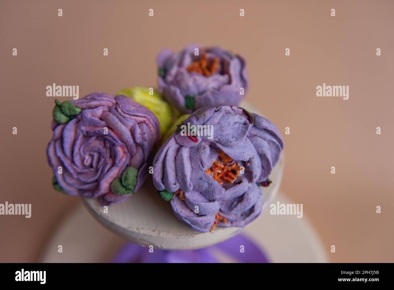 Auf einem runden Holzhintergrund liegen natürliche Marshmallows in Form von violetten Pfingstrosen. Süße Desserts ohne Zucker. Kreative Backwaren. Stockfoto