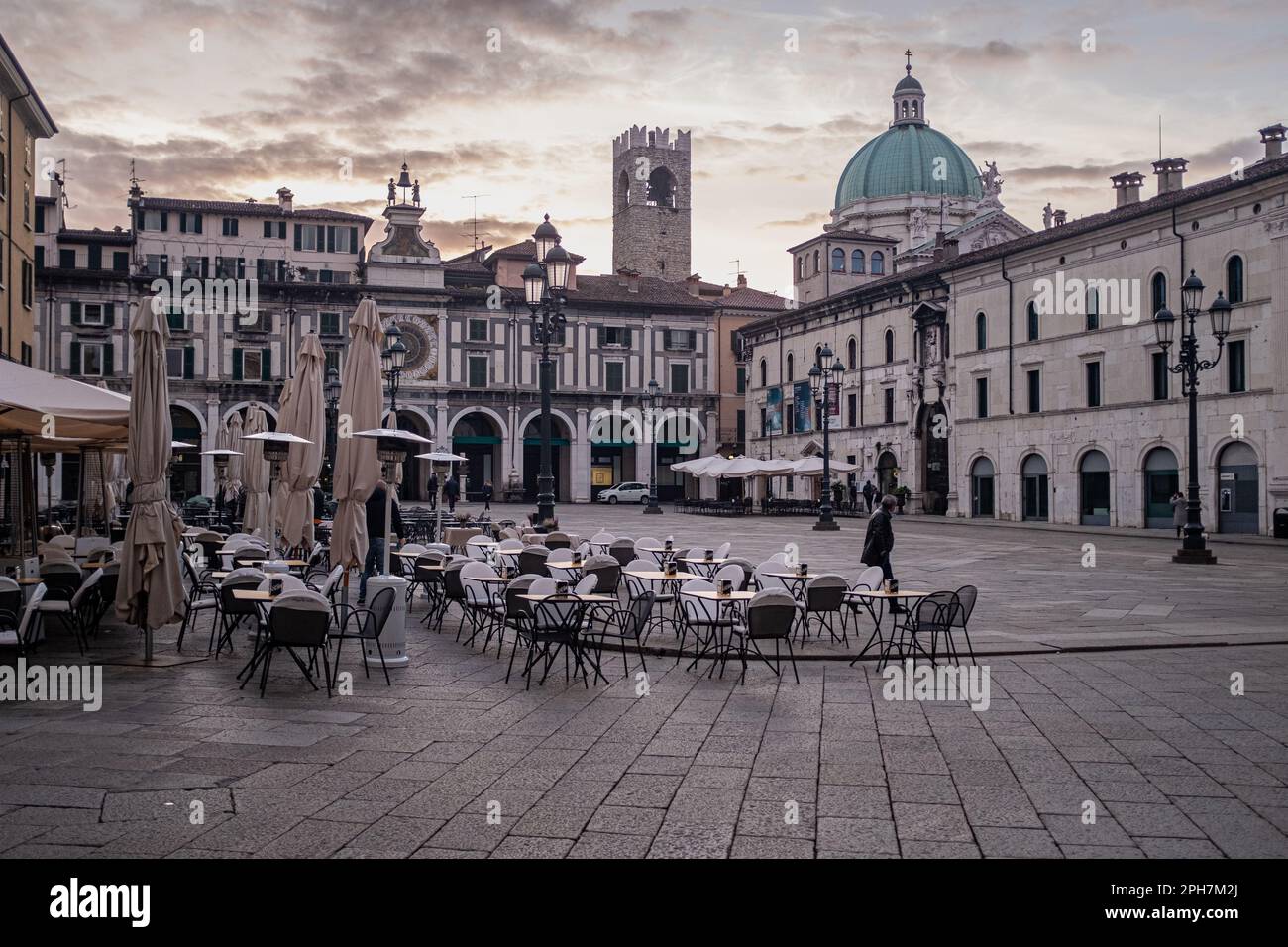 Ein Blick auf die Piazza della Loggia in Brescia (Italien) bei Sonnenaufgang am Morgen. Die Renaissance-Arkaden und der Turm mit der Uhr im Hintergrund. Stockfoto