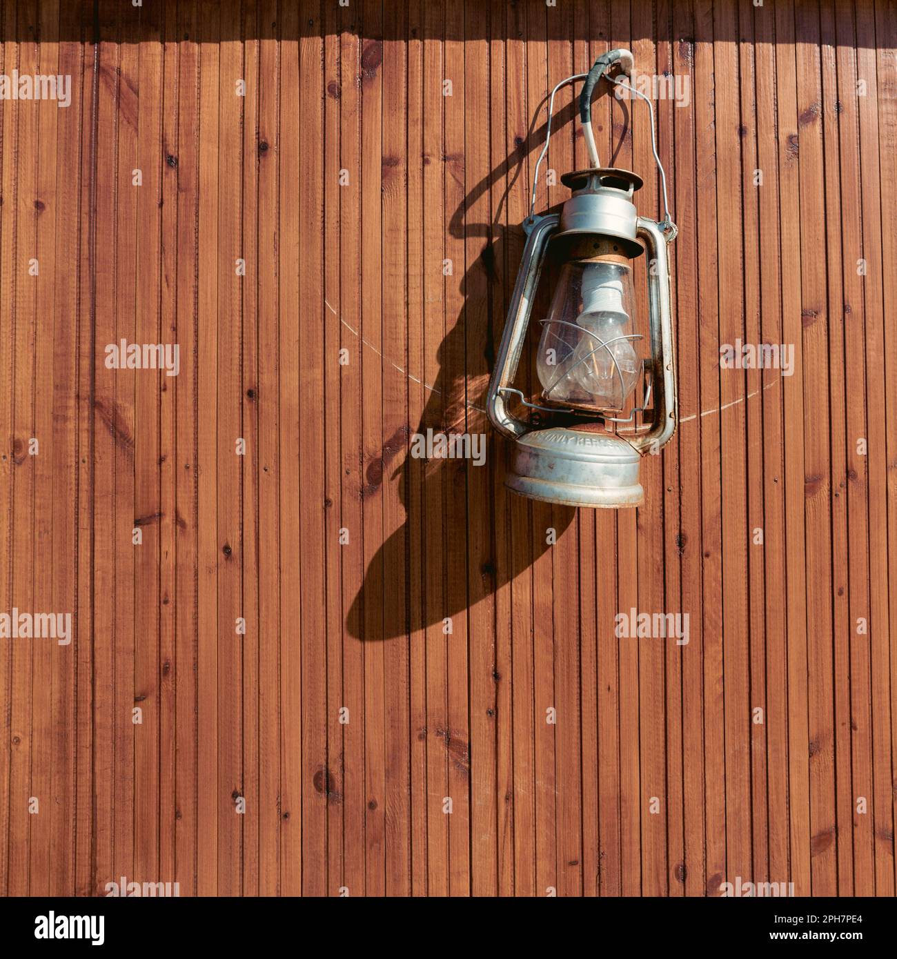 Alte rustikale Laterne hing an einer gelben Holzwand Stockfoto