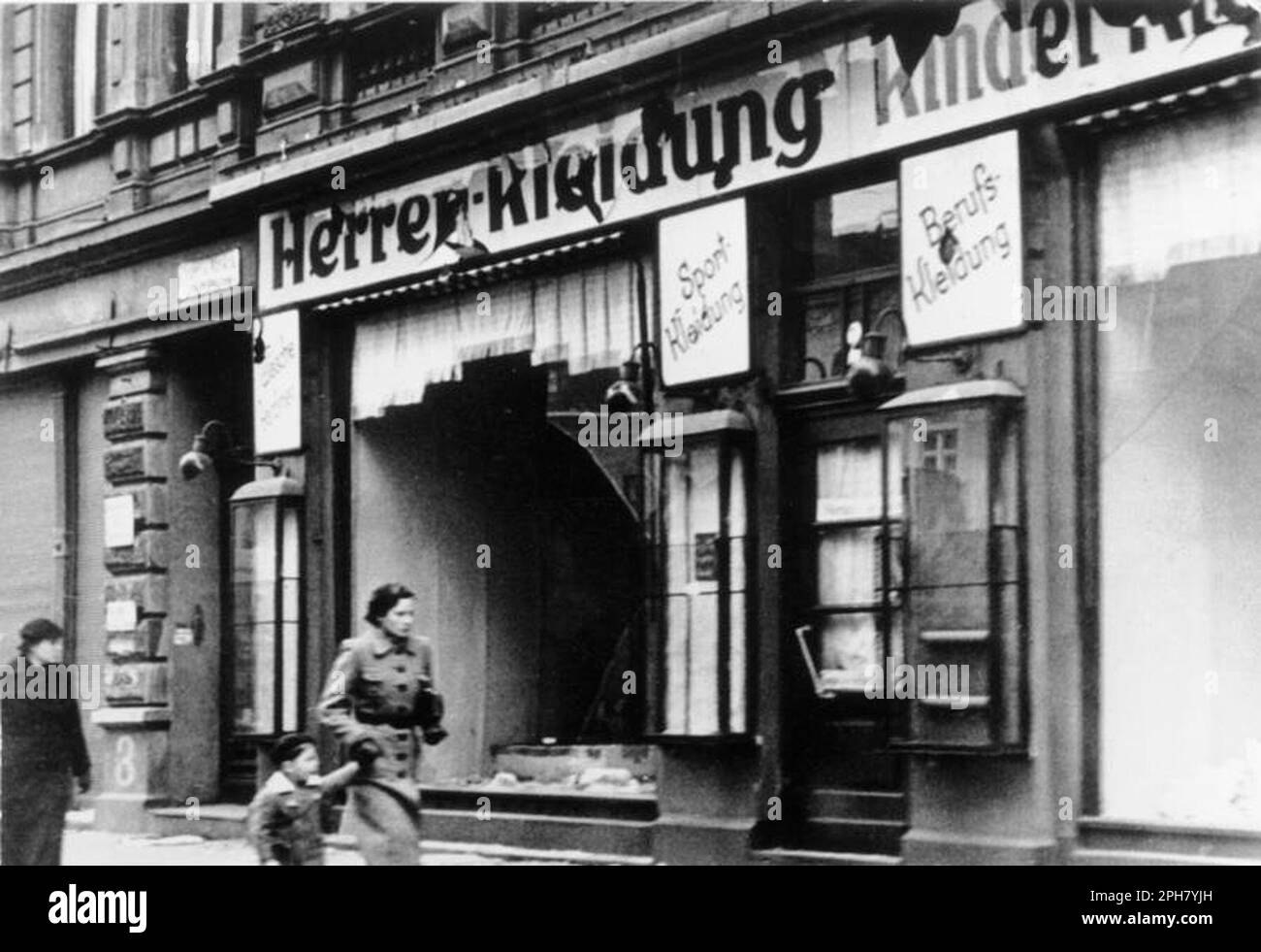 Leute, die an zertrümmerten jüdischen Geschäften in Magdeburg vorbeilaufen. Kristallnacht war ein landesweites Pogrom, das am 9. November 1938 von der nazi-Partei organisiert und durchgeführt wurde. Geschäfte und Synagogen wurden zerstört und Menschen gedemütigt und geschlagen, während die Polizei zuschaute oder sogar half. Obwohl die Schäden und die Zahl der Angreifer recht gering waren, zeigte die Tatsache, dass sie völlig unangefochten waren, den Nazis, dass sie wirklich mit den Juden anfangen konnten, und ist damit einer der wichtigsten Meilensteine auf dem Weg zum Holocaust. Bundesarchiv, Bild 146-1970-083-44/Friedrich, H./CC-BY- Stockfoto