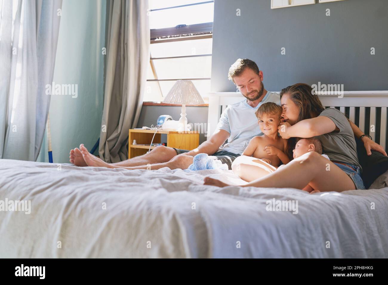 Morgenzeit Familienzeit. Eine junge vierköpfige Familie, die sich im Schlafzimmer anfreundet. Stockfoto