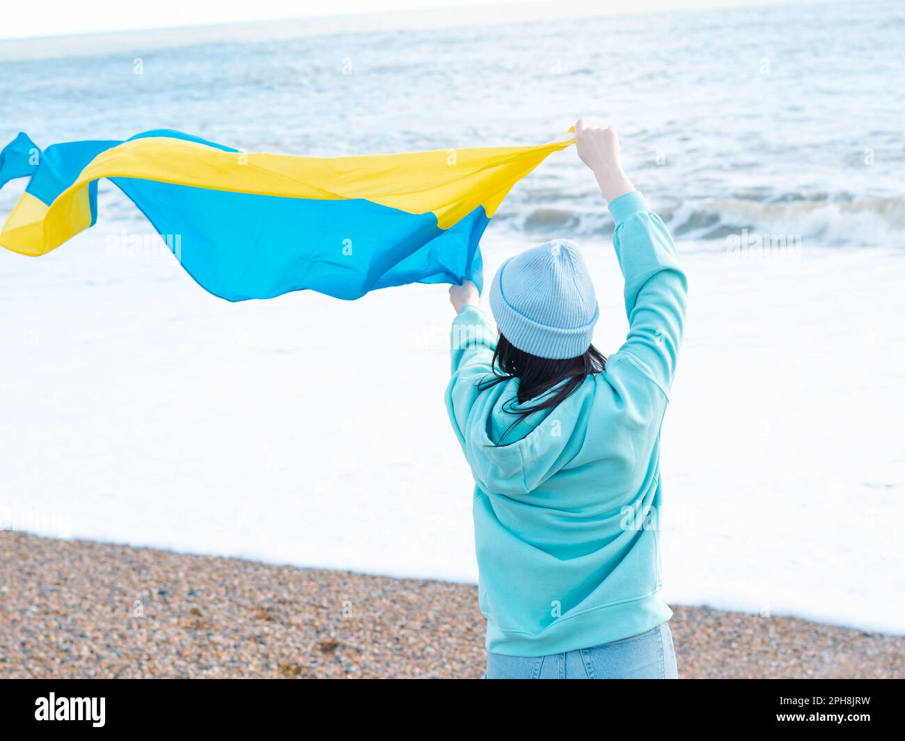 Braune Frau in blauem Hoodie und blauem Hut mit ukrainischer Nationalflagge, patriotisches Konzept Stockfoto