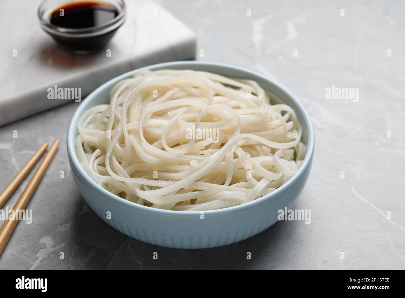 Schüssel mit Reisnudeln serviert auf grauem Tisch Stockfoto