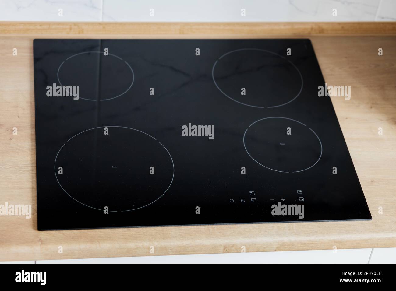 Moderne Küche mit schwarzem Induktionskochfeld oder Elektroherd mit Keramikoberfläche und Holzarbeitsfläche Stockfoto