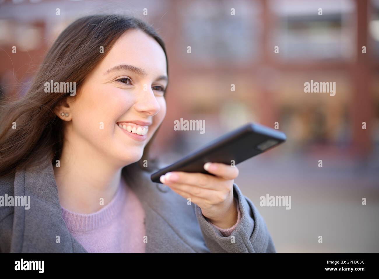 Glückliche Frau im Winter diktiert Nachricht am Telefon Stockfoto