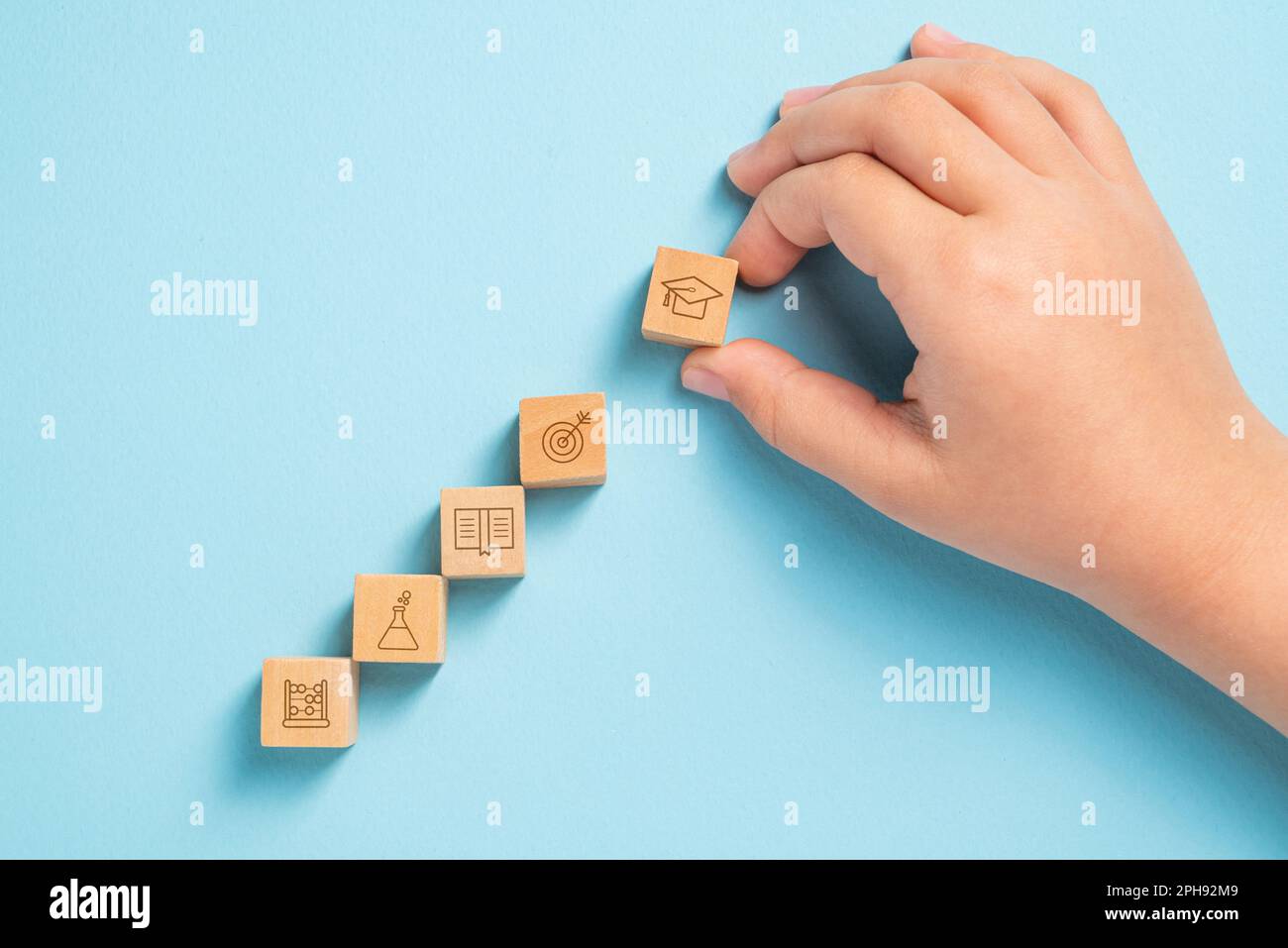 Schüler, die Holzwürfel mit Bildungs-Ikonen organisieren. Bildungskonzept Stockfoto