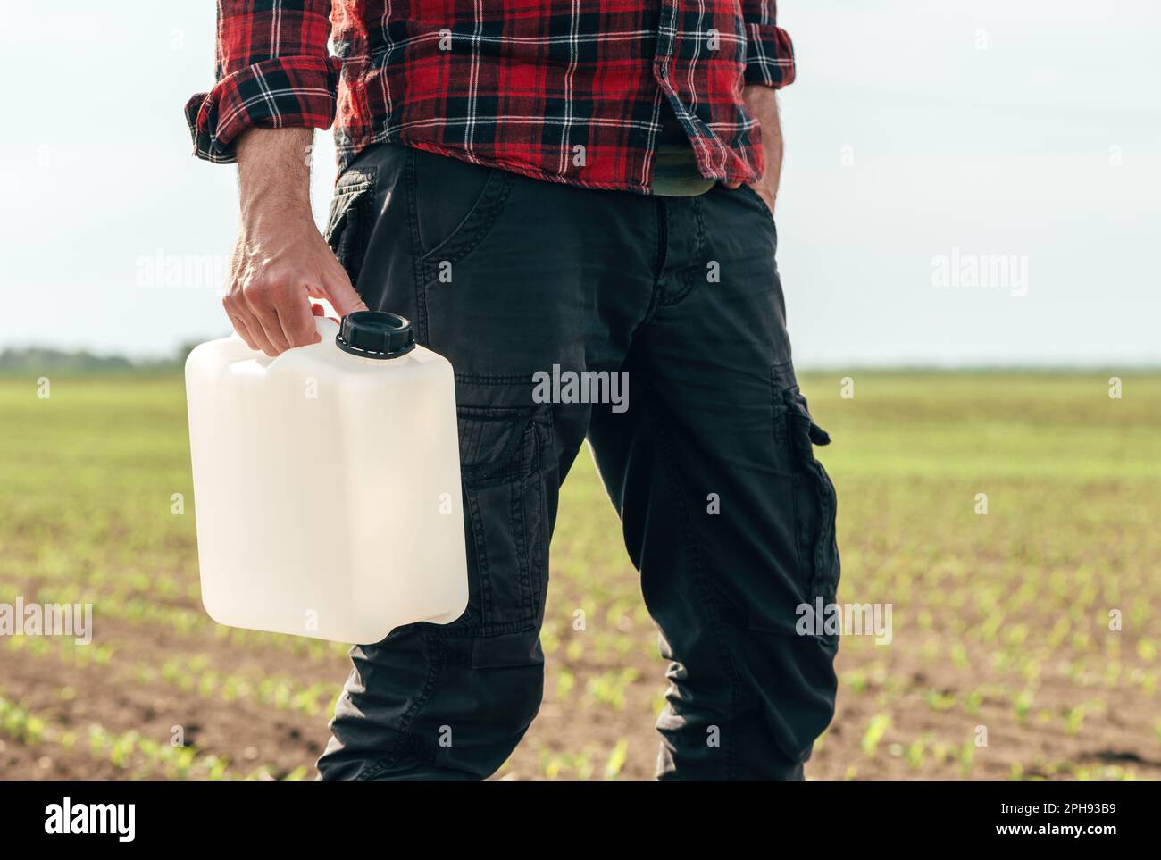 Maispflanzenschutzkonzept, Landwirt-Agronom hält jerry Can Behälter Kanister mit Pestizid, selektiver Fokus Stockfoto