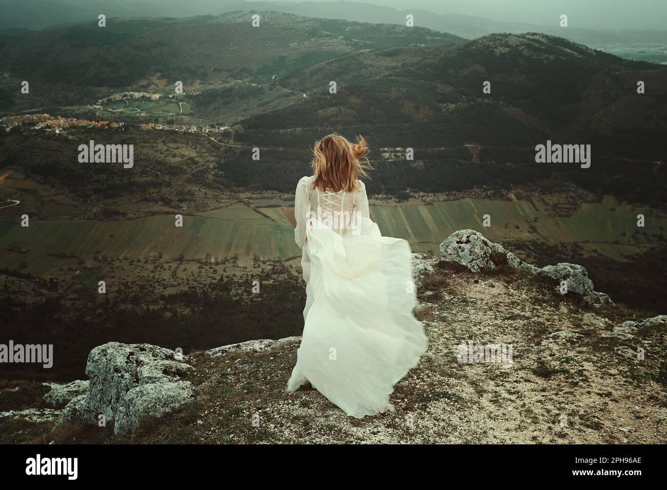 Eine Frau mit altem Kleid auf einem einsamen Berggipfel Stockfoto
