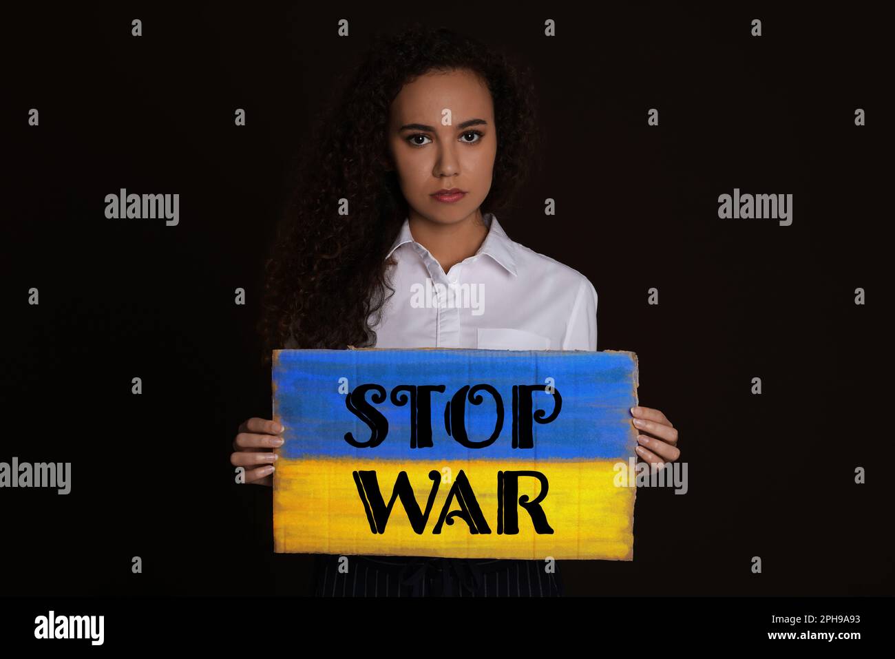 Eine unglückliche afroamerikanische Frau mit einem Schild mit der Phrase "Stop war" auf schwarzem Hintergrund Stockfoto