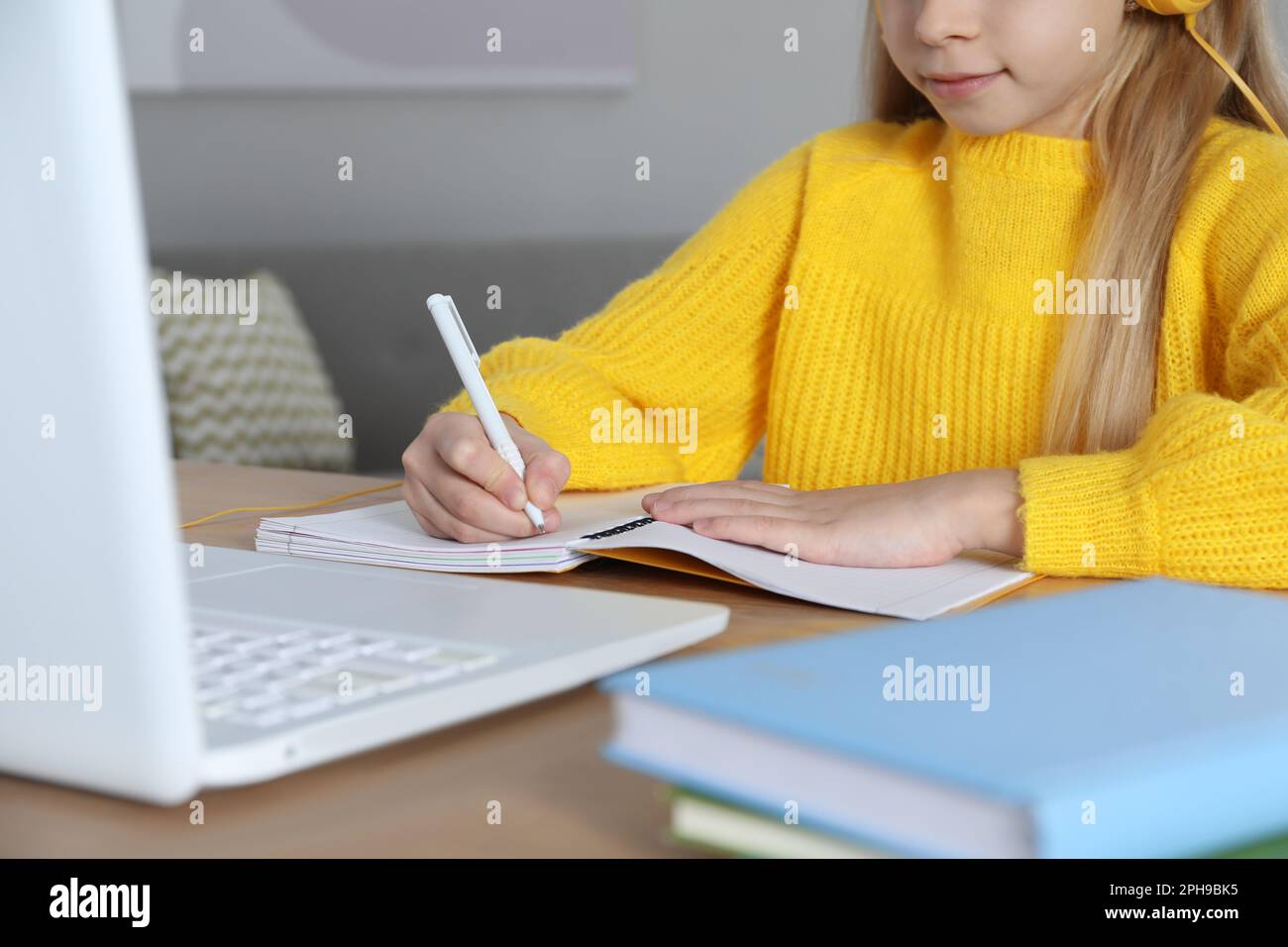 Süßes kleines Mädchen mit modernem Laptop, das zu Hause online lernt, Nahaufnahme. E-Learning Stockfoto